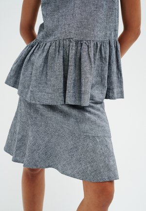 Top peplum en lin gris avec des accents froncés et une jupe évasée. Tissu texturé avec un motif subtil, design longueur genou.