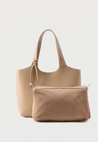 Τσάντα tote από μπεζ δέρμα με επιμηκυμένες λαβές, που διαθέτει θήκη με φερμουάρ στο ίδιο χρώμα, και τα δύο με λείο υφή και λιτό σχεδιασμό.