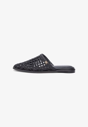 Black woven leather slip-on mule with flat sole and small gold decorative logo on upper side.