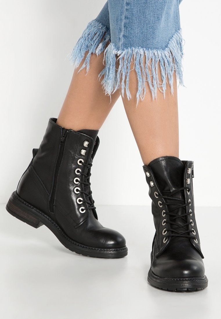 Bottes courtes en cuir noir avec devant à lacets, œillets argentés et fermeture éclair. Surface texturée et détail de talon en bois.