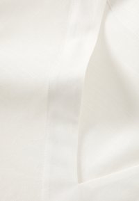 Teren alb din material cu o textură netedă, având un luciu subtil și un model de țesătură în diagonală. Include secțiuni suprapuse și detalii de cusătură ordonate.