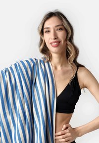 Blue and white striped fabric draped over one shoulder, made of a lightweight material, contrasting with a black top. Smooth texture.