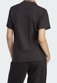 Svart bomull T-shirt med korta ärmar, rund halsringning och en jämn textur. Inga märkbara mönster eller detaljer. Endast bakvy.