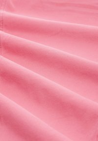 Tissu rose doux avec des plis lisses et réguliers, et des coutures visibles le long du bord gauche, mettant en valeur la texture et la couleur.
