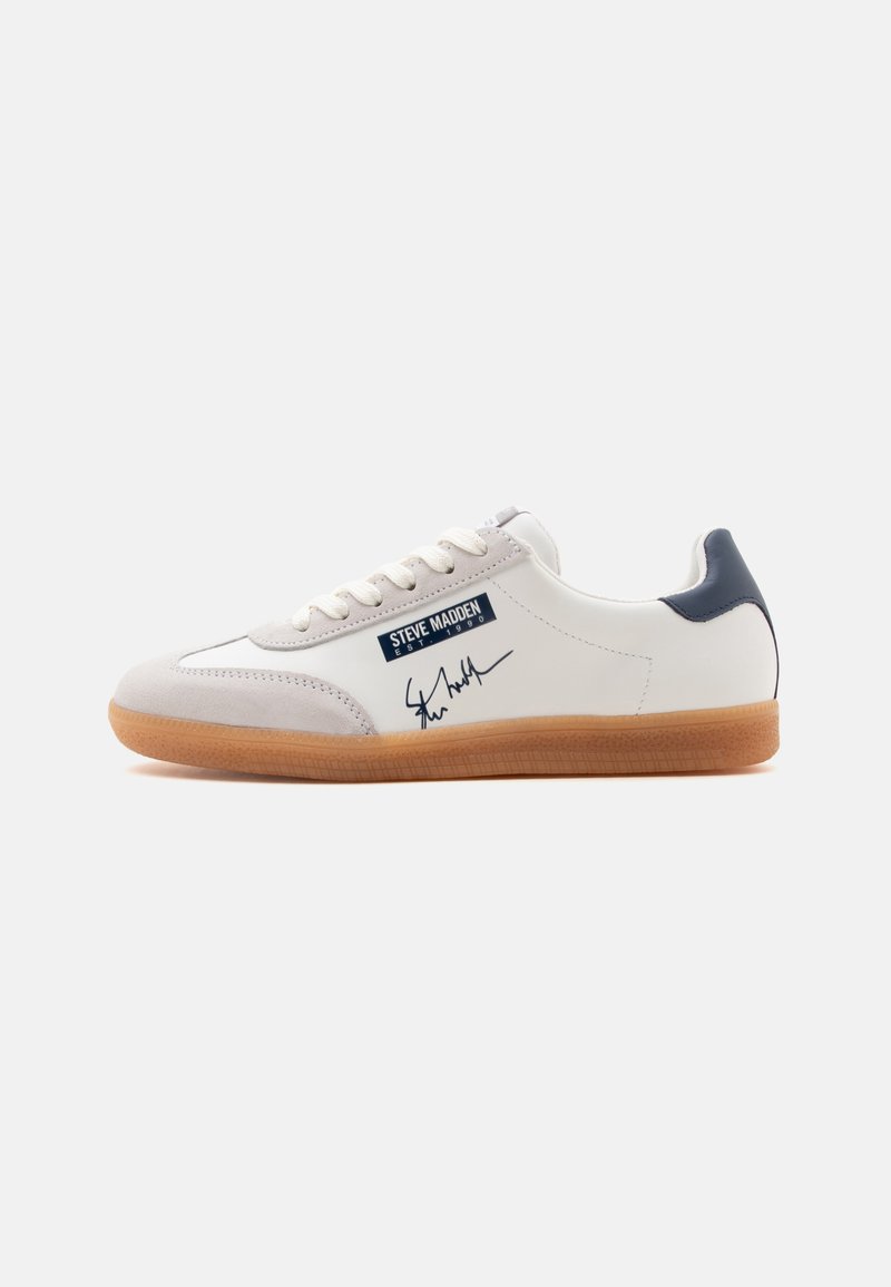 Baskets basses blanches avec embout beige, languette de talon bleu marine, semelle en gomme, lacets et logo "Steve Madden" avec signature sur le côté.