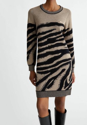 Beige and black zebra-print long-sleeve knitted dress worn with black textured knee-high boots, shown from neck to knees.