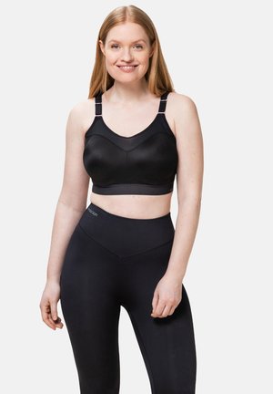 Zwarte sportbeha met een gladde textuur, brede banden en een V-vormige halslijn. Gekleed met hooggetailleerde zwarte legging met een naadloos ontwerp.