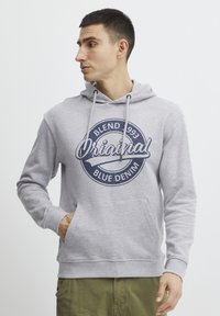 Šedá mikina vyrobená z bavlněné směsi, s přední kapsou a modrým grafickým logem s textem. Design zahrnuje kapuci se šňůrkou.