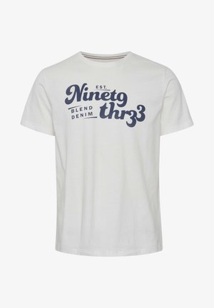 Camiseta de algodón blanca con mangas cortas, que presenta un texto impreso en azul oscuro que dice "EST. Ninetg thr3e BLEND DENIM" en varios tamaños.