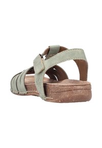 Zielone skórzane sandały z teksturowaną korkową podeszwą, regulowanym paskiem i krzyżującym się wzorem. Widok z tyłu ukazuje otwartą piętę i wyściełaną wkładkę.