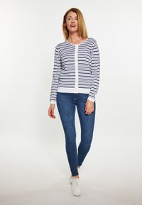 Cardigan rayat în alb și bleumarin, cu închidere prin butoni, mâneci lungi; asortat cu blugi skinny albaștri și adidași albi. Țesătură netedă.