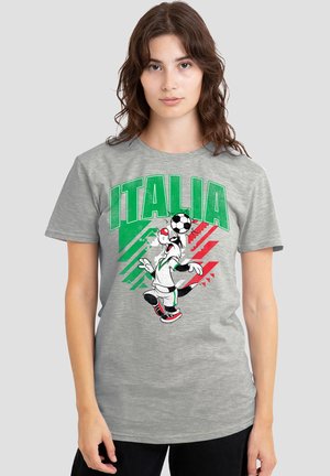 Frau trägt ein graues T-Shirt mit dem Text "ITALIA", eine animierte Hundefigur balanciert einen Fußball und grüne sowie rote grafische Streifen.
