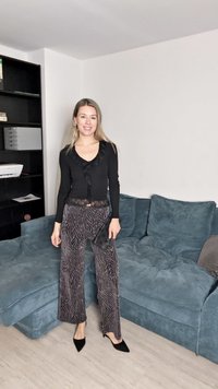 Musta pitkähihaine paita, jossa on röyhelökoristeita, yhdistettyinä leveisiin zebra-kuosisempiin housuihin. Mustat kärkitossut täydentävät asua.