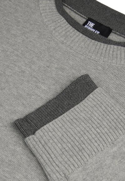 Grauer Pullover mit einem gerippten Halsausschnitt und Bündchen, der an den Bündchen einen dunkleren grauen Akzent hat. Weiche Textur, elegantes Design.
