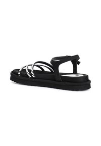 Sandalia negra con múltiples correas brillantes, adornada con tachuelas plateadas. Presenta una suela acolchada y una correa trasera ajustable para un ajuste seguro.