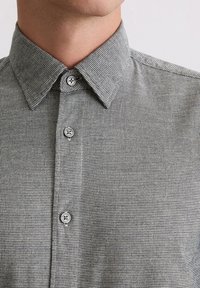 Grau-weißer karierter Button-Up-Hemd mit strukturiertem Kragen und texturierter Stoffstruktur. Verfügt über runde Knöpfe entlang der Knopfleiste.