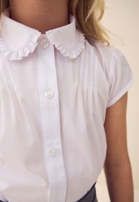 Weiße Bluse mit gerafftem Kragen, kurzen Ärmeln und vertikalen Biesen. Verfügt über eine Knopfleiste und besteht aus glattem, leichtem Stoff.