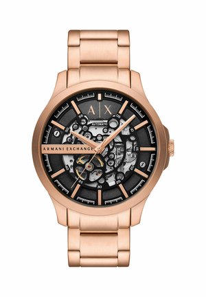 Montre-bracelet Armani Exchange en or rose avec cadran squelette noir, mouvement automatique visible et bracelet en métal à maillons.