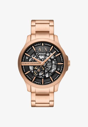 Montre-bracelet Armani Exchange en or rose avec cadran squelette noir, mouvement automatique visible et bracelet en métal à maillons.