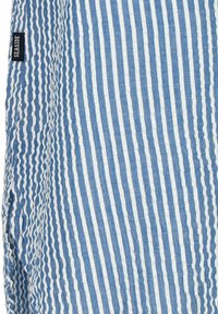 Tessuto a righe blu e bianche con una texture increspata. Include un'etichetta nera con la scritta "SEASIDE" sul lato.