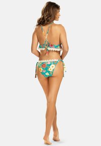 Dwuczęściowy strój kąpielowy w kwiatowy wzór na turkusowym tle, z koronkowymi akcentami. Górna część ma regulowane ramiączka i falbany.