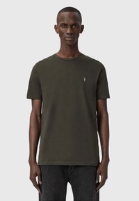 Tummanvihreä lyhythihainen T-paita, joka on valmistettu puuvillasta. Sen ominaisuuksiin kuuluu pyöreä pääntie ja pieni brodeerattu logo vasemmalla rinnalla.