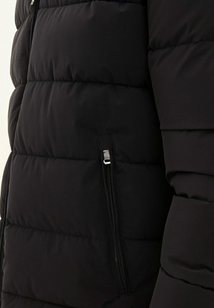 Giubbotto imbottito nero con motivo trapuntato, texture liscia e tasca laterale con zip sul lato sinistro.