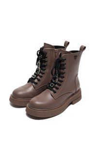 Botas de tobillo de cuero marrón con suela texturizada, cordones decorativos y ojetes, cremallera lateral y tiradores en la parte superior para facilitar el uso.