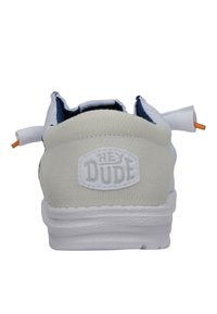 Zapatilla blanca de malla con un tacón redondeado, que presenta una suela de goma texturizada y un logo en relieve de "HEY DUDE" en la parte trasera. Acentos en naranja presentes.