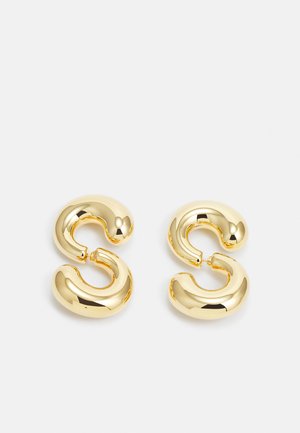 Gold-tone hoop earrings with a smooth, shiny surface; features a curved, abstract design resembling a stylized letter "S."