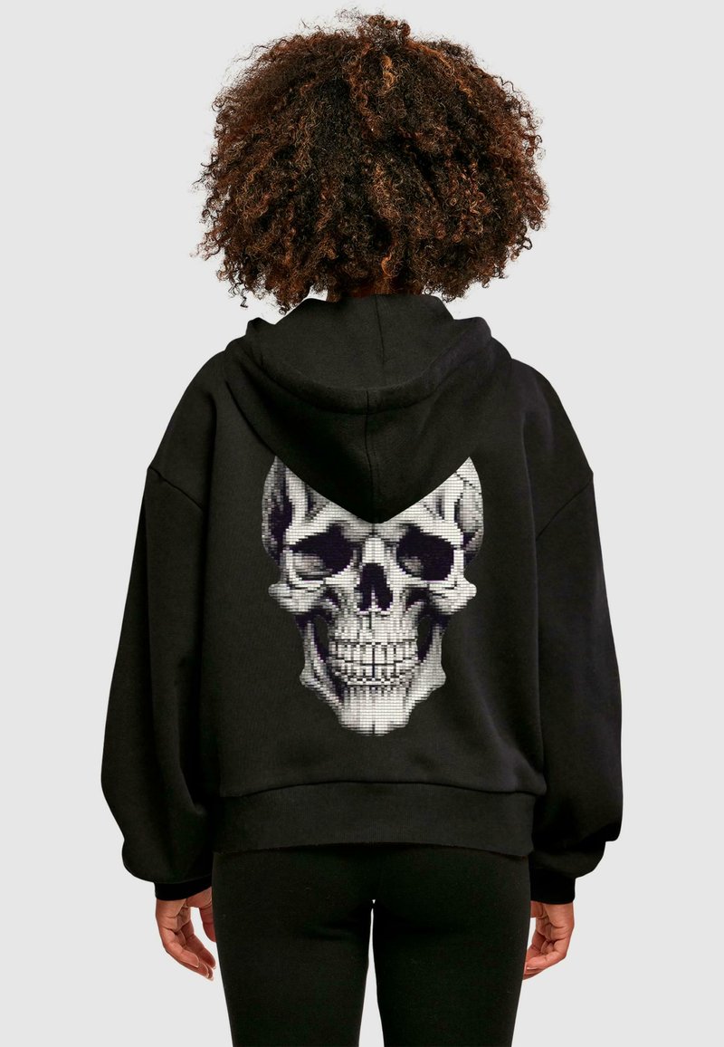 Sudadera con capucha negra que presenta un gran gráfico de calavera en la parte posterior. Hecha de un material suave con un corte relajado y puños acanalados.