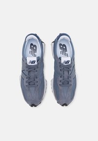 Šedé sportovní boty vyrobené z materiálů síťoviny a semiše, s tónovanými tkaničkami, polstrovaným límcem a bílým logem na modré stélce.