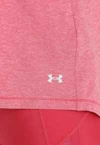 Camiseta deportiva rosa hecha de tela texturizada, con un logo blanco. El dobladillo es curvado, con costuras visibles a lo largo de los bordes.