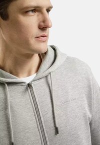 Szara rozpinana bluza z kapturem, wykonana z miękkiego materiału, z regulowanym kapturem i subtelnym logo na piersi. Gładka faktura, nowoczesny design.