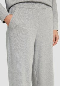 Grijze geribde sweatpants hebben een relaxte pasvorm met zijzakken en een elastische tailleband. De stof heeft een zachte, gestructureerde afwerking.