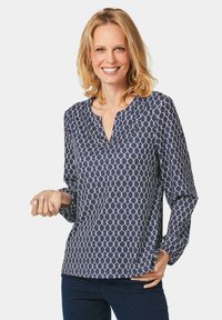 Dunkelblaue Bluse mit Muster, einem Notch-Kragen, langen Ärmeln und weißen geometrischen Designs, aus leichtem Stoff gefertigt.