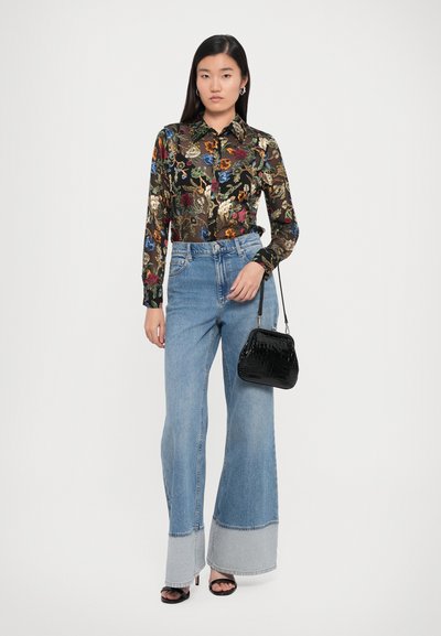 Black floral blouse with long sleeves, blue wide-leg jeans with contrasting hem, black textured handbag, and black high-heeled sandals.