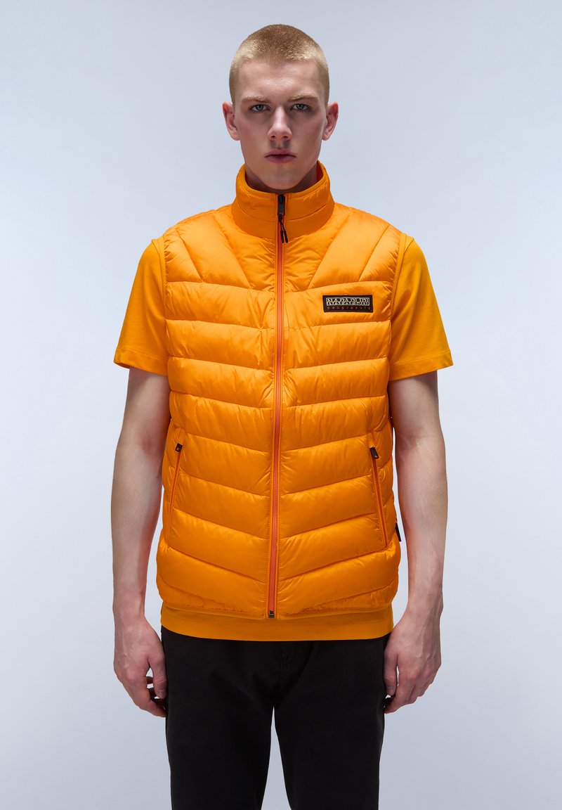 Pomarańczowa kamizelka puchowa z wysokim kołnierzem, pikowanym wzorem i zamkiem z przodu. Posiada boczne kieszenie oraz małą naszywkę z logo na piersi.