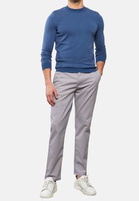 Blå åtsittande tröja, ljusgrå byxor med subtil textur och vita sneakers. Ren design med ribbade mudd och midjeband.