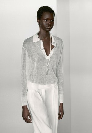 Haut en tricot léger et transparent de couleur gris clair avec un col blanc et des détails de boutons, associé à un pantalon blanc. Design simple avec une texture minimale.