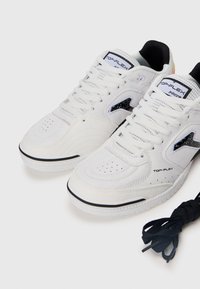 Baskets blanches avec des accents noirs, des détails perforés et du cuir texturé. Caractéristiques : un col rembourré et des lacets noirs.
