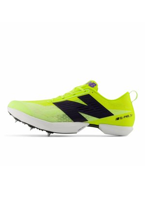 Fel geelgroene New Balance hardloopschoen met spikes, met zwart logo, witte zool en metalen spikes aan de voorkant en bij de hiel.