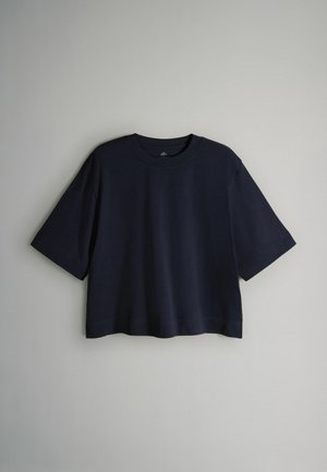 Tricou cropped albastru marin din bumbac moale, cu decolteu rotund și mâneci scurte, având un croi lejer. Design minimalist, fără modele.