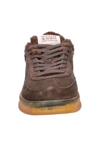 Brown suede sneaker with a round toe, lace-up front, padded collar, and a translucent rubber sole. Features a brand logo on the tongue.