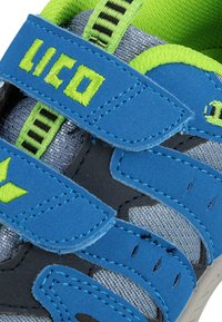 Chaussure de sport bleu et noir avec des sangles Velcro, tige en textile gris, accents verts et détails contrastants en noir et vert.