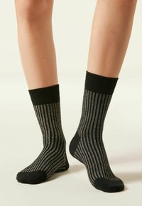 Schwarz-graue gestreifte Socken mit einer gerippten Textur, die einen dicken schwarzen Bund und einen glatten Fußbereich aufweisen, der ein minimalistisches Design betont.
