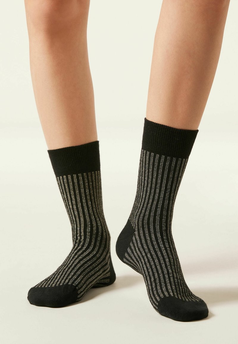 Schwarz-graue gestreifte Socken mit einer gerippten Textur, die einen dicken schwarzen Bund und einen glatten Fußbereich aufweisen, der ein minimalistisches Design betont.