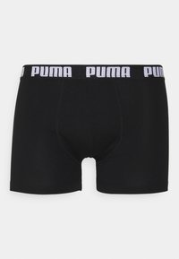 Black boxer shorts made from elastic fabric, featuring a white logo band at the waist. Smooth texture and fitted design with a mid-thigh length.