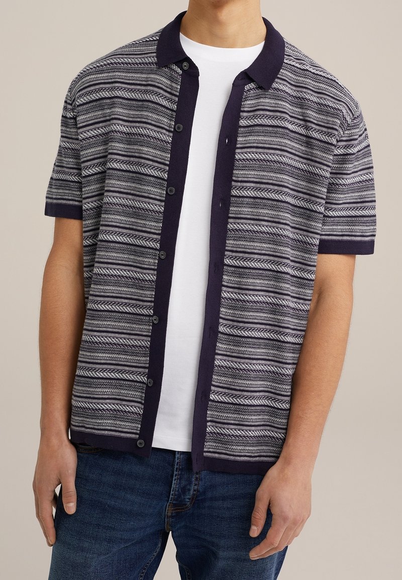 Chemise à manches courtes à boutons en bleu marine avec un motif rayé blanc et gris, présentant un col contrastant et un tissu texturé.