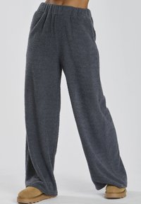 Grå, fluffy loungbukser med løst fit, elastisk linning og sidelommer, lavet af blødt, struktureret stof.